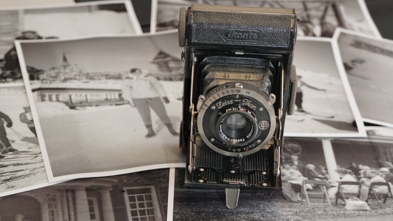 Antique film camera on stack of black and white pictures