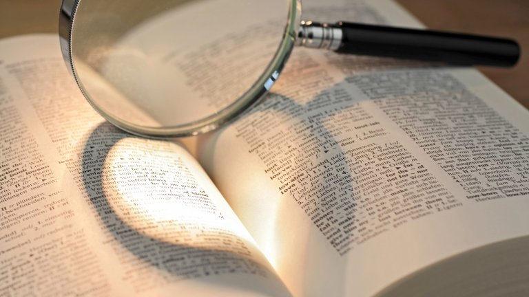 Magnifying glass resting in open dictionary