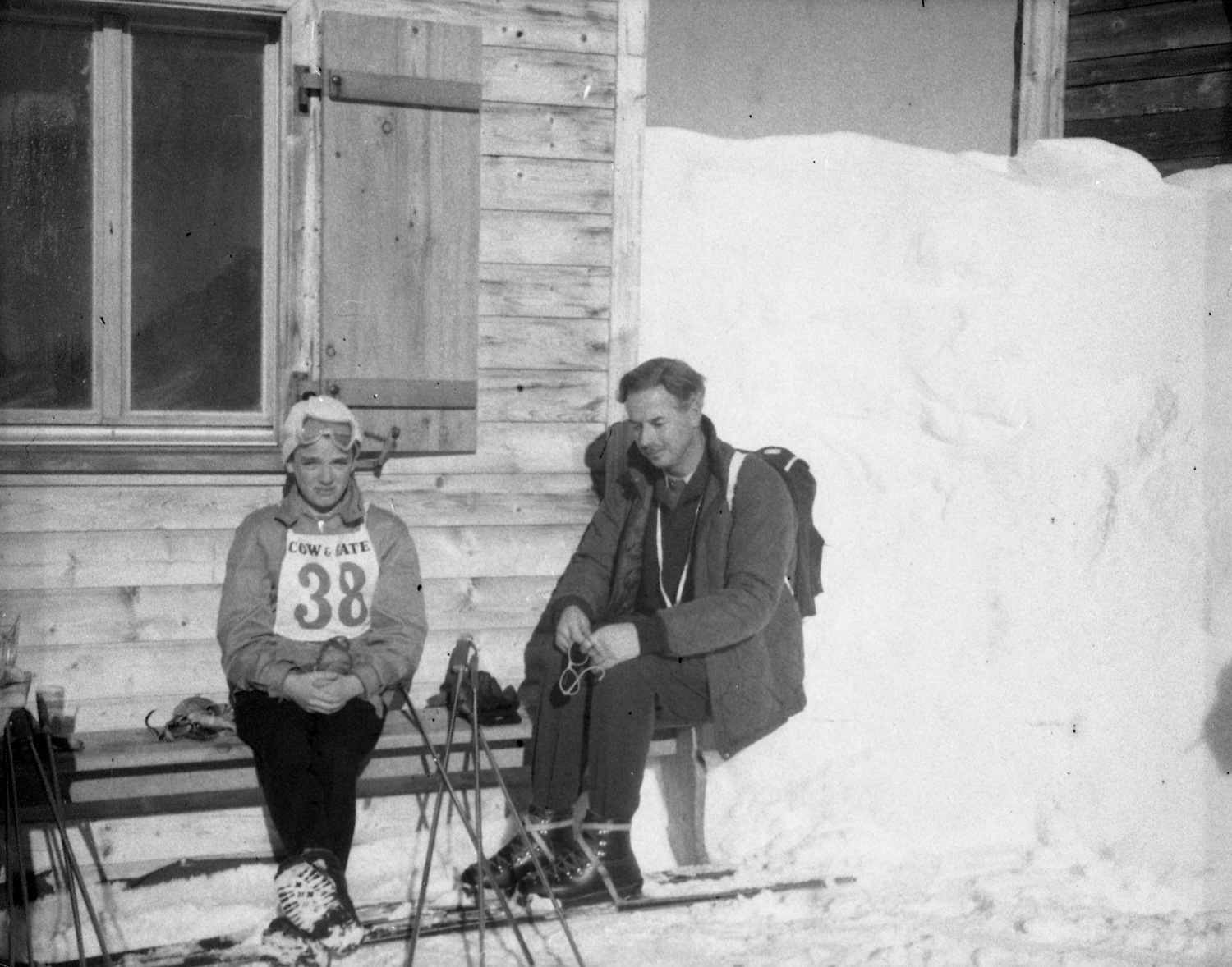 Man and young girl sitting next to each other on ski slope