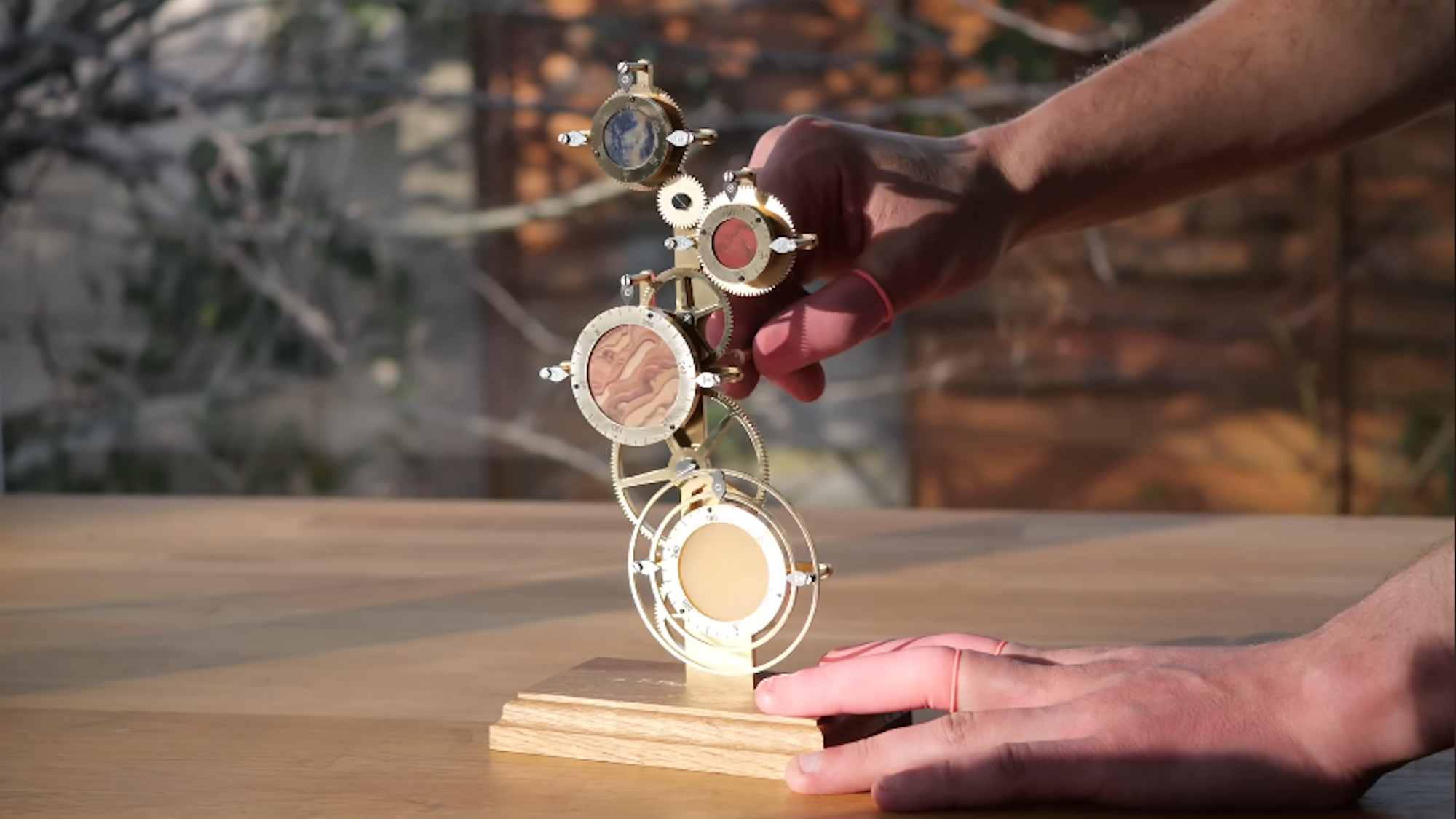 Handing winding a series of brass gears that comprise an interplanetary clock device