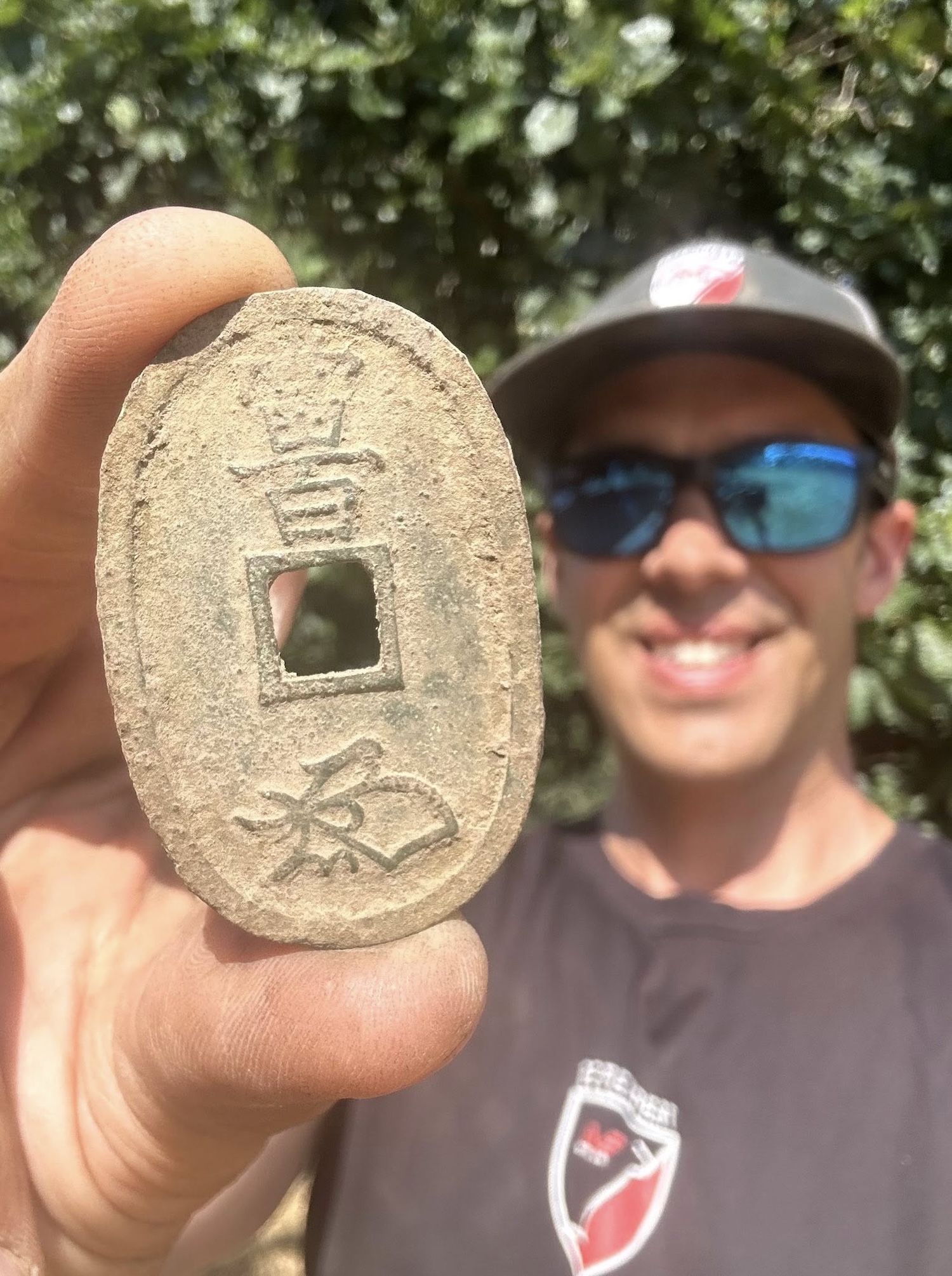 Man holding 19th century Japanese coin and smiling