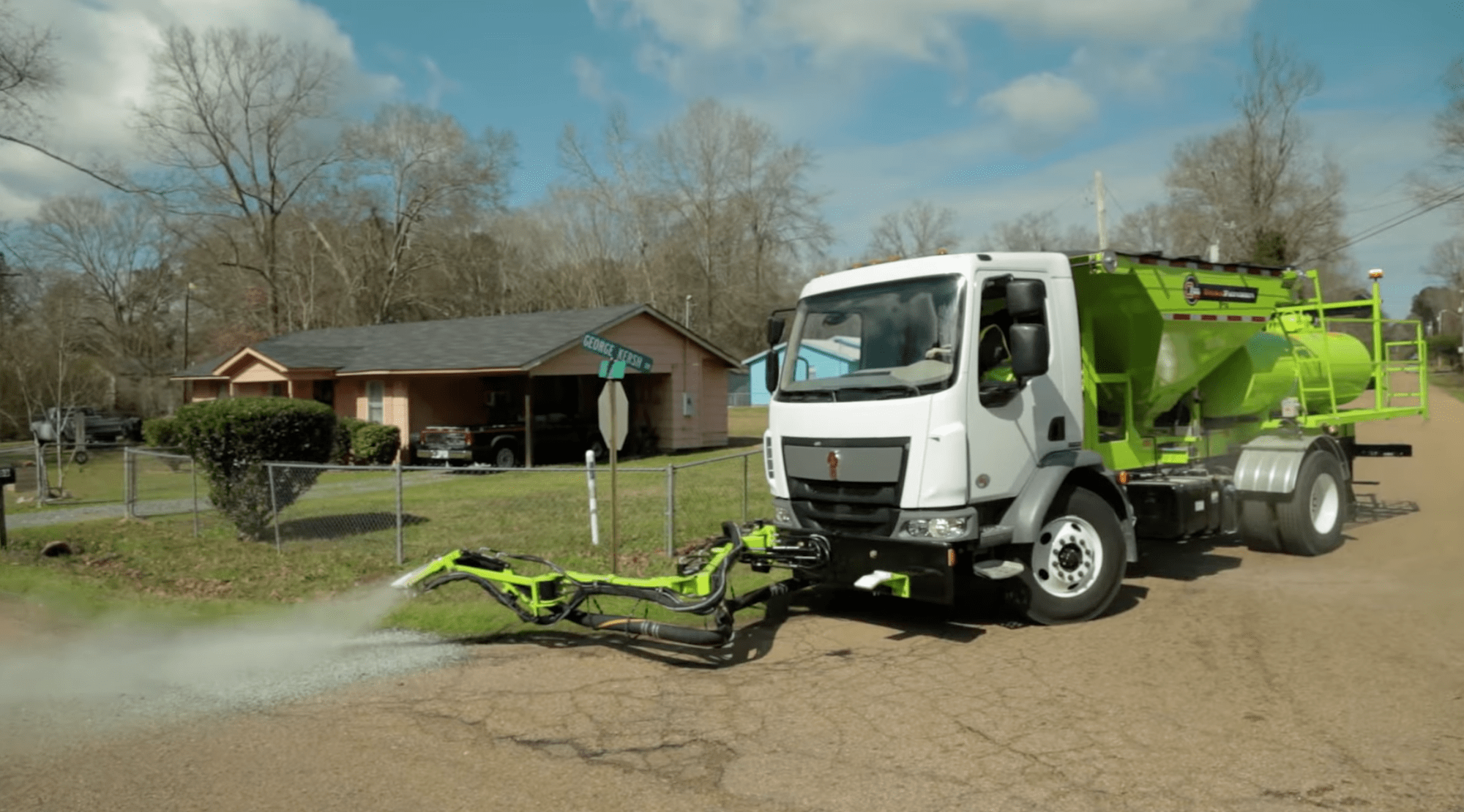 a truck spraying a pothole in front of a house
