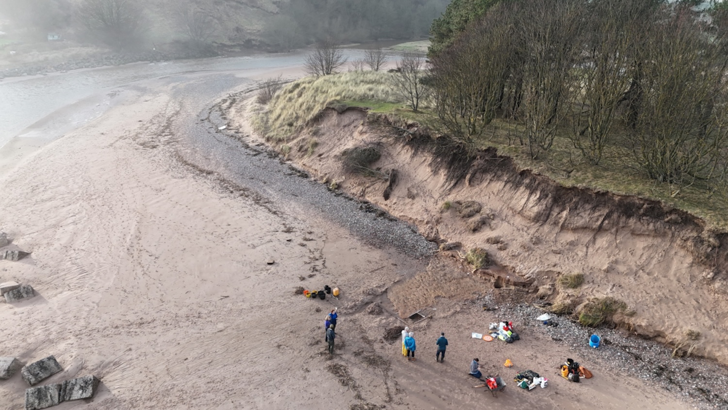 Aerial shot of archaeologists excavating along Scottish beach