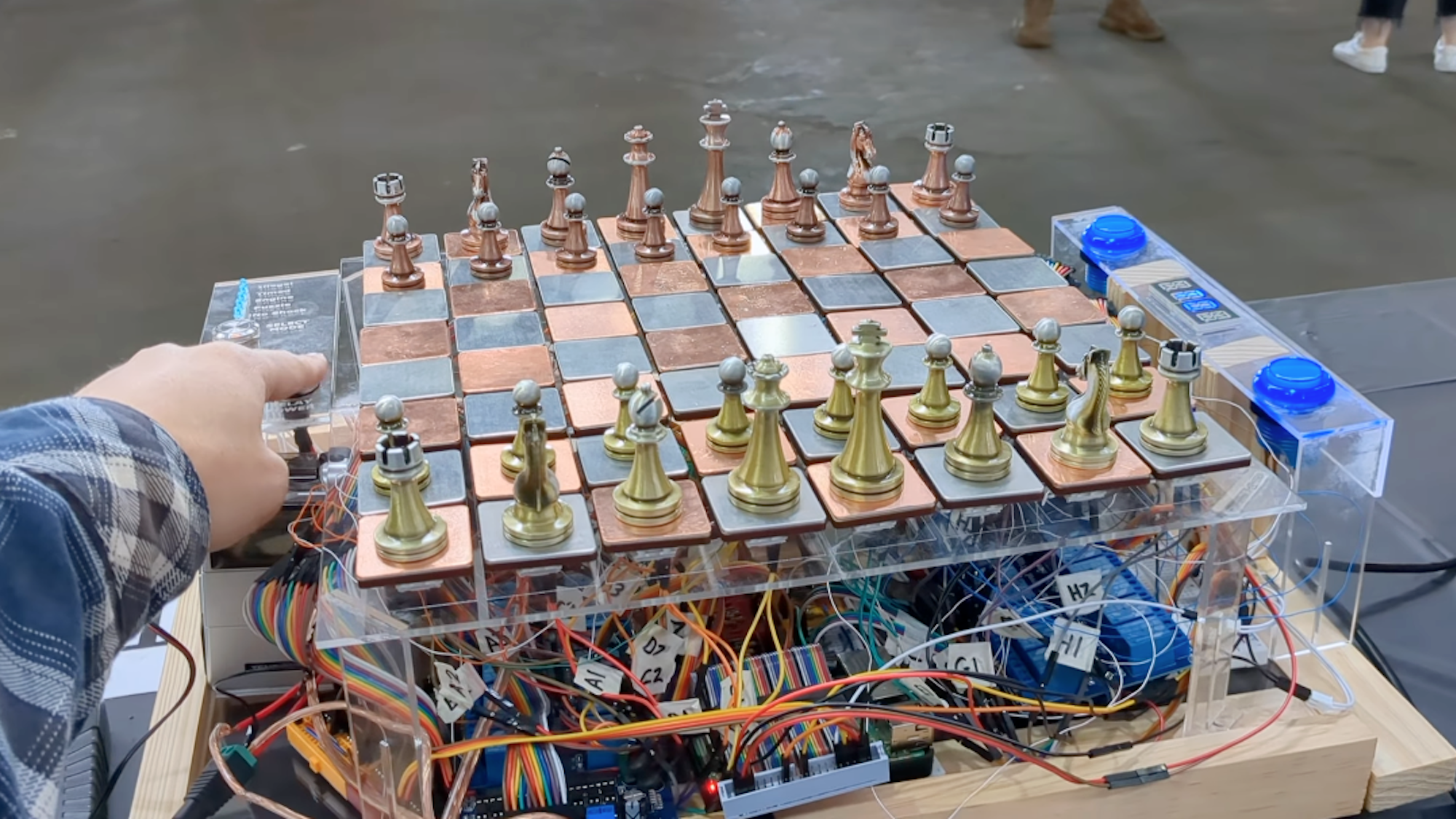 Hand pointing at DIY electric chessboard with bunches of wires underneath it