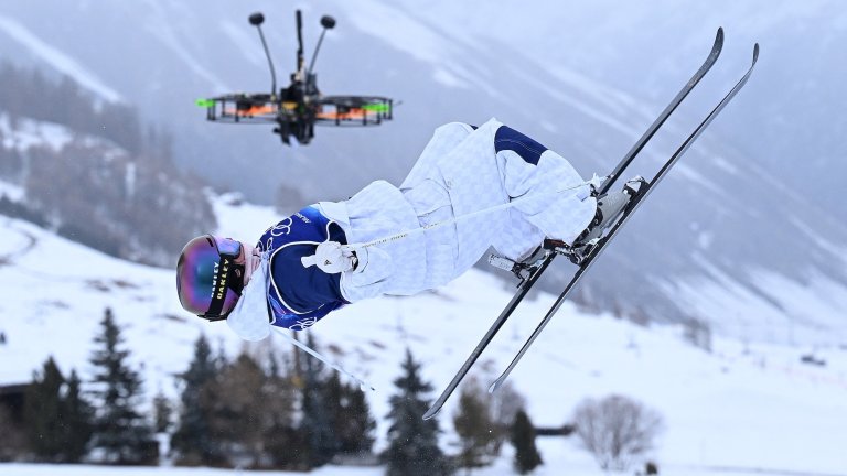 A broadcast drone hovers as Britain's Makayla Gerken Schofield competes in the freestyle skiing women's moguls qualification 1 during the Milano Cortina 2026 Winter Olympic Games at Livigno Aerials & Moguls Park, in Livigno (Valtellina), on February 10, 2026. (Photo by Kirill KUDRYAVTSEV / AFP)