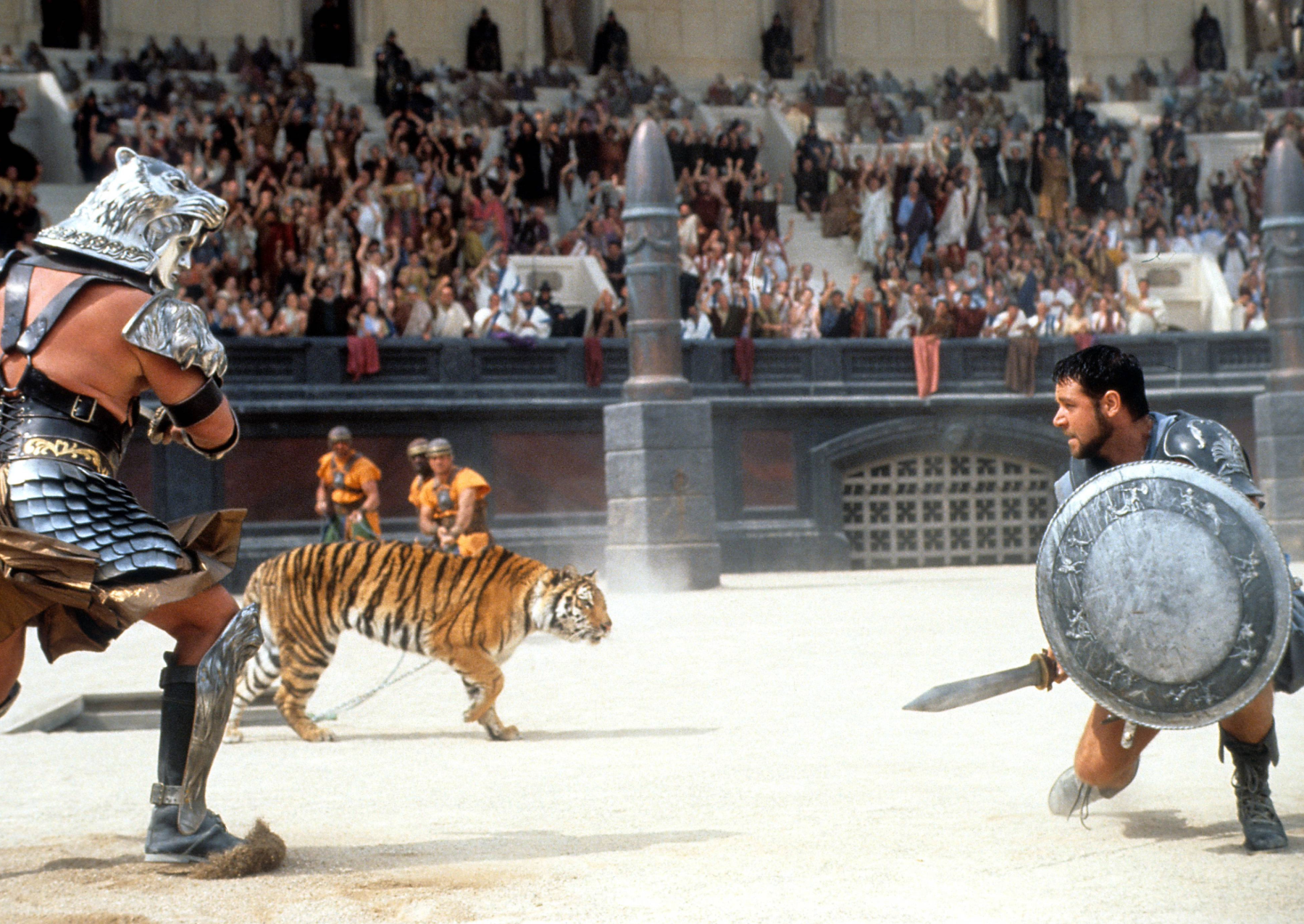 a scene from the 2000 film gladiator. two men are fighting with swords, with a tiger nearby