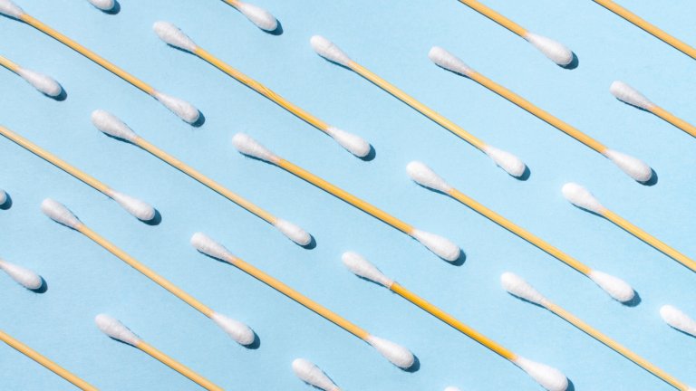 Directly avobe view of many wooden ecological cotton swabs on a blue colored background