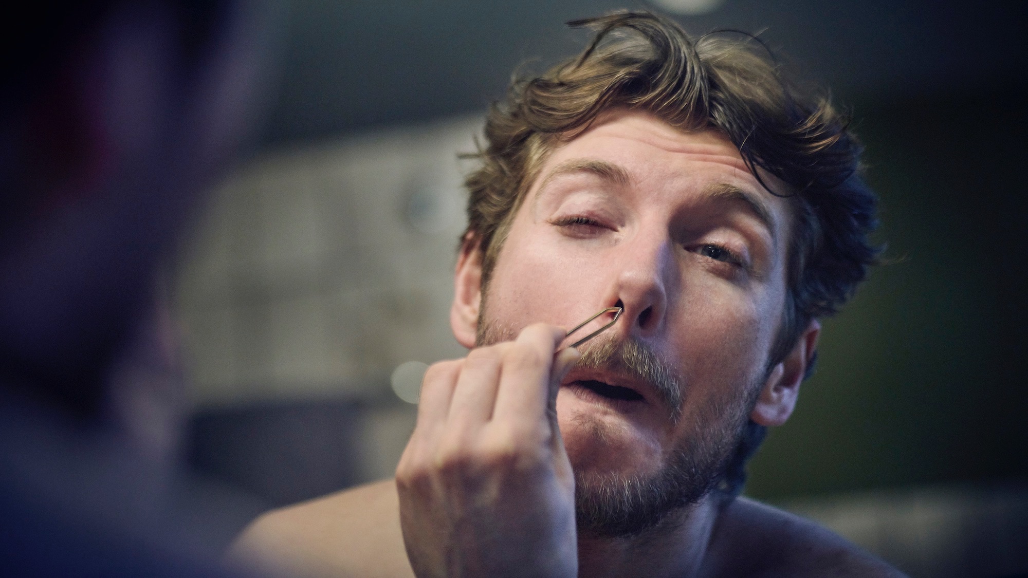 Young man plucking the hair out of the nose