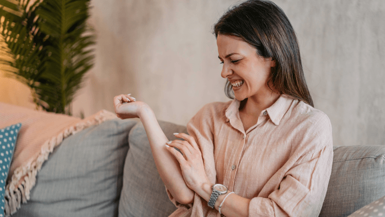 a woman scratches an uncomfortable itch on her forearm