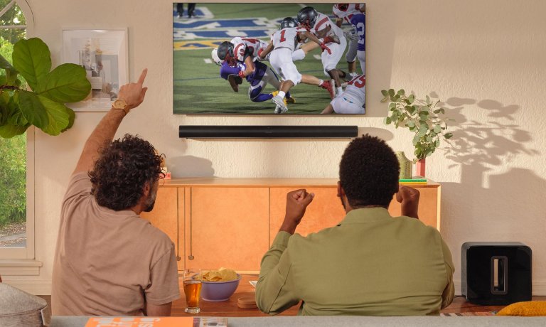 People watching football on a TV paired with a Sonos soundbar that's on sale
