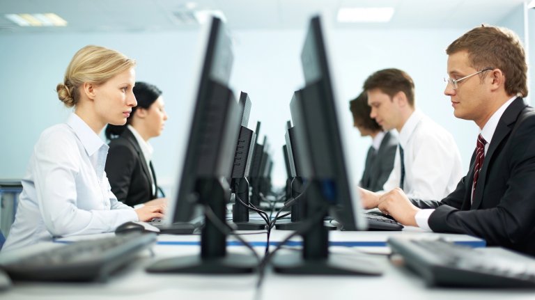 Two rows of businesspeople working on computers