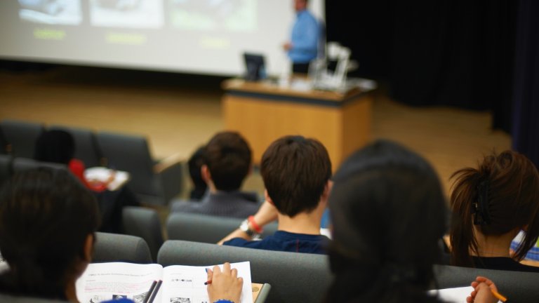 students watch professor in lecture hall