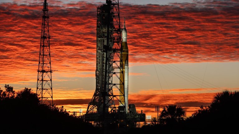 Clouds and the Sun illuminate the sky on Wednesday, Jan. 28, 2026, as NASA’s Artemis II SLS (Space Launch System) rocket and Orion spacecraft stand vertical at Launch Complex 39B at NASA’s Kennedy Space Center in Florida.