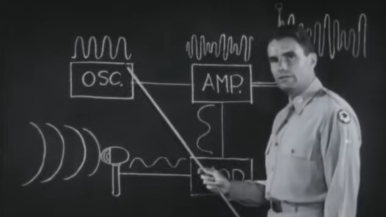 Man pointing with stick at chalkboard diagram of AM radio setup