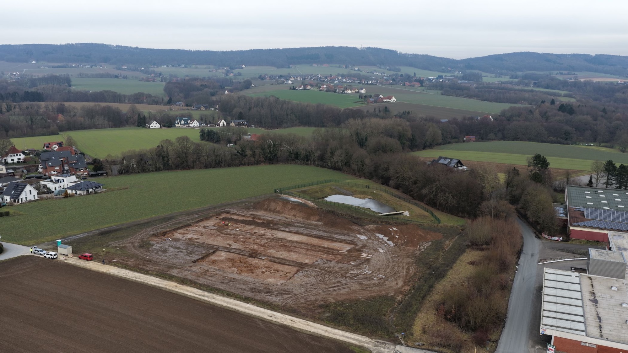 Aerial photograph of the excavation area for the new fire station building on Lohagenweg in Hüllhorst. The tree cover marks the course of the source stream, which formed the basis for the construction of the former farmstead. Photo: LWL-AfW / A. Koch