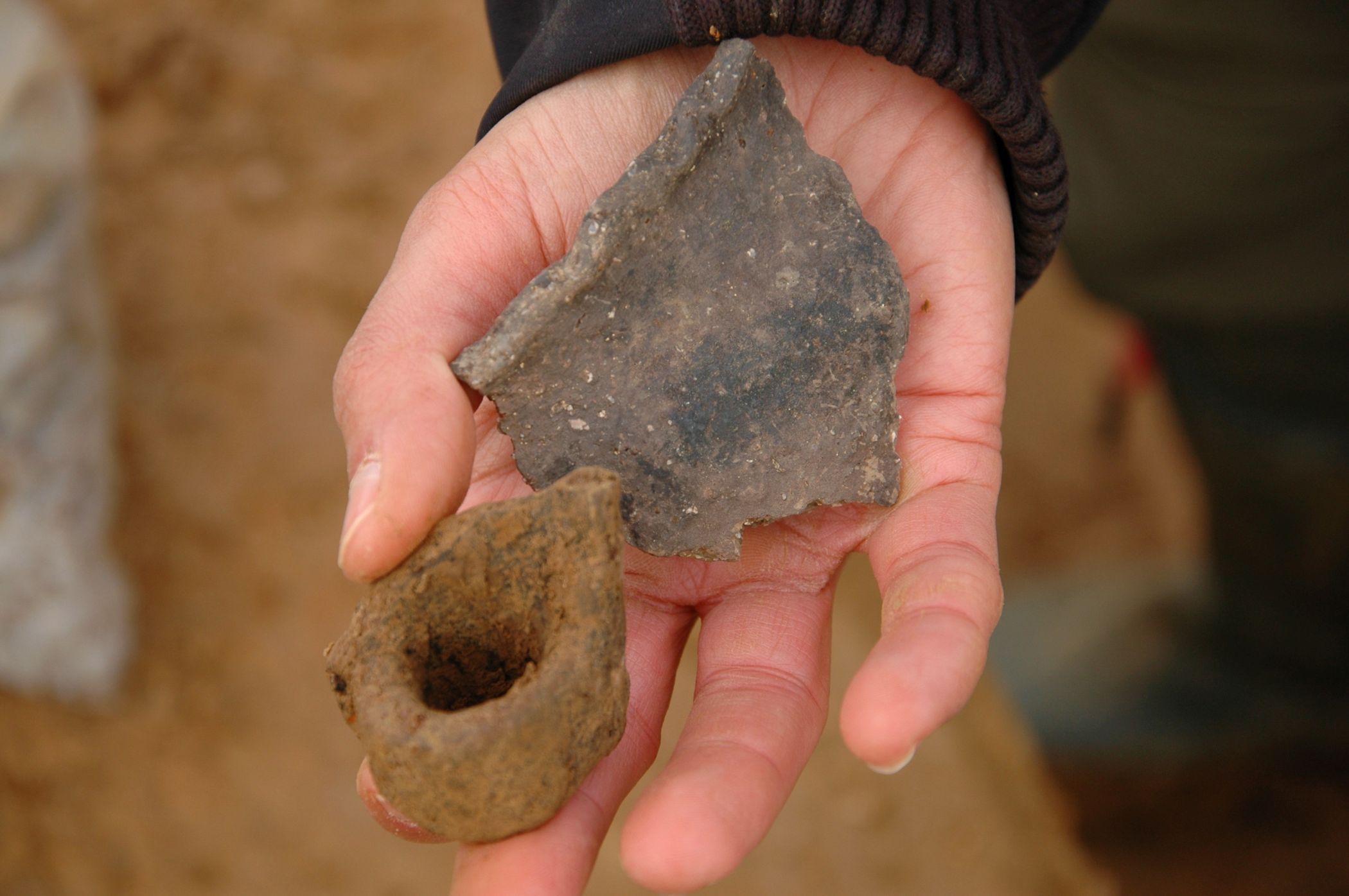 Typical vessel shards of the early Iron Age: a rim decorated with finger dots and a fragment with a wide rimmed handle. Credit: LWL-AfW / S. Düvel