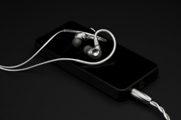 The titanium Meze Audio ASTRU IEMs shown resting on a digital audio player against a black background