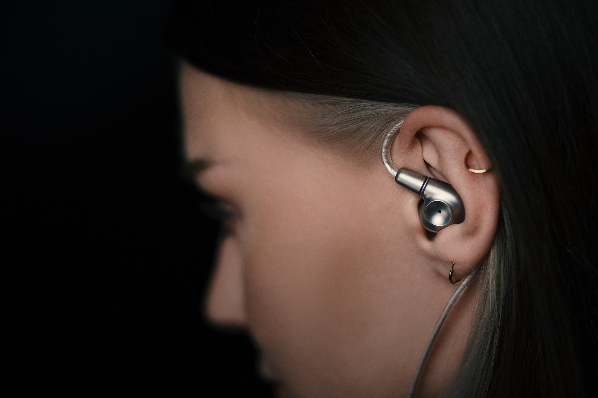 A close-up of the titanium shell Meze Audio ASTRU in a woman's ear