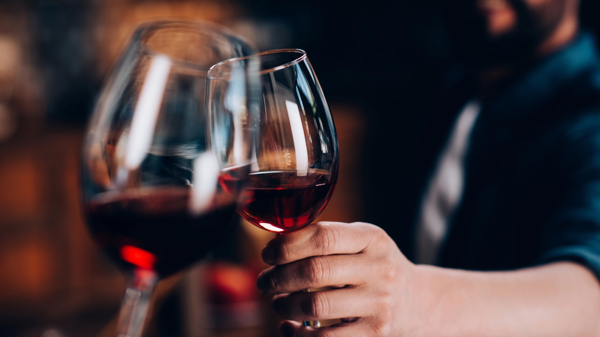 Close up of two people clinking together red wine glasses