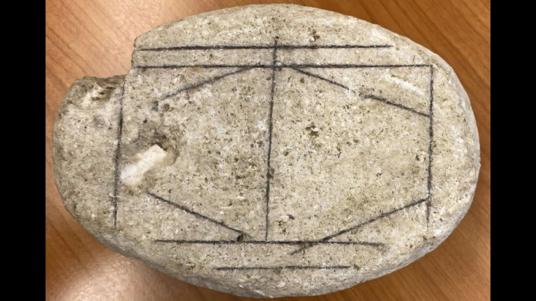 Oval limestone with line etchings that likely represent a board game played in ancient Rome