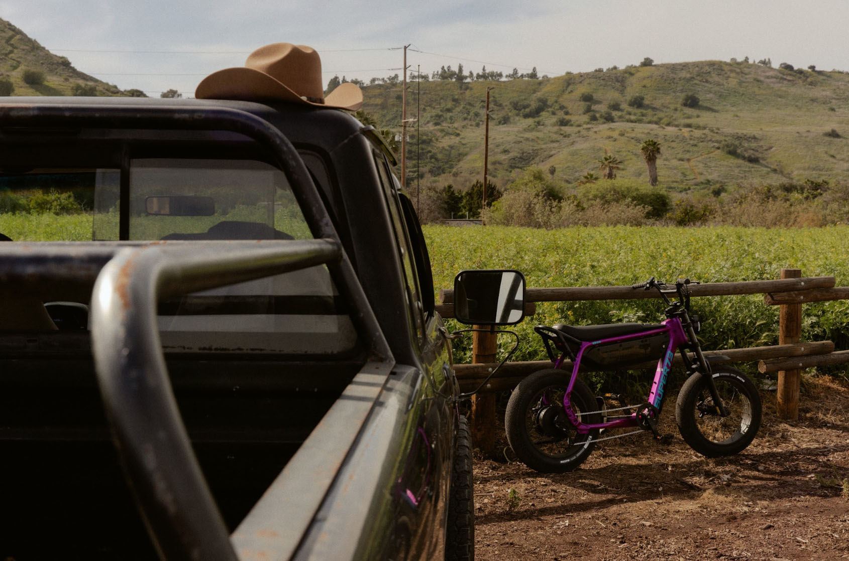 A SUPER73 A-Series B1G model in Cullenberry leaning against a fence near a pick-up truck