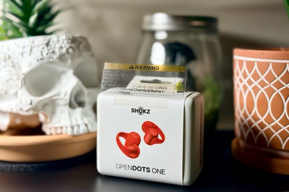 Red SHOKZ OpenDots One package sitting on a shelf between planters