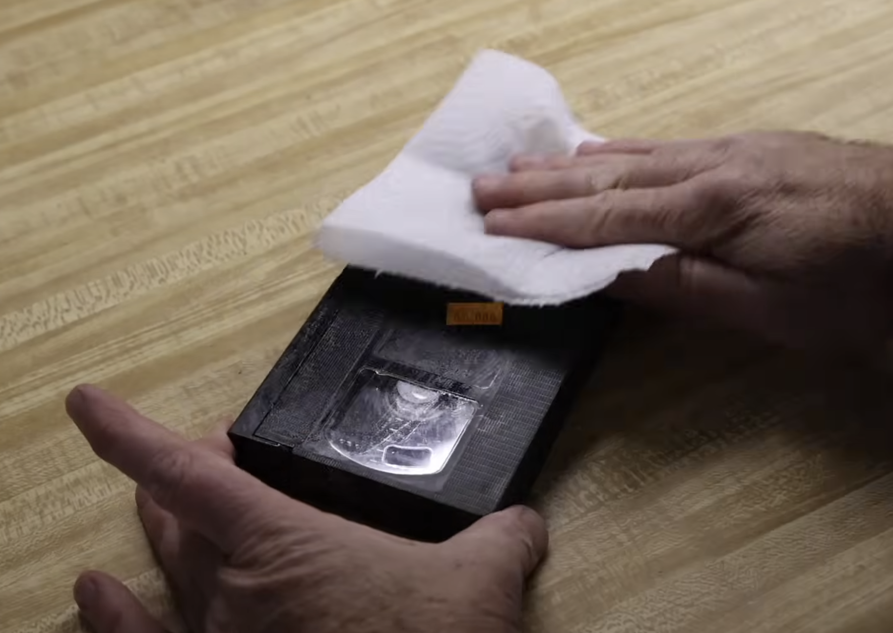 wiping down a VHS tape with a towel