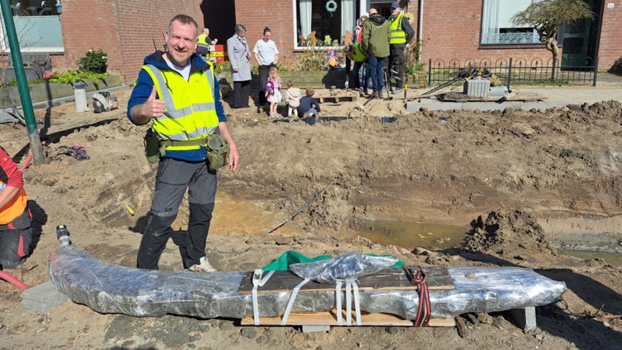 Man giving thumbs up next to Viking age ship beam