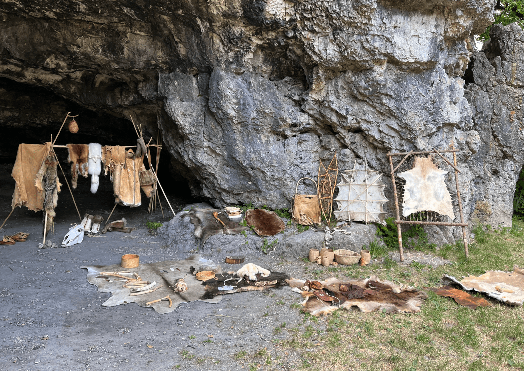 Reenactment scene in front of the Kesslerloch cave in Thayngen, Switzerland. Pelts are seen drying outside of a cave with baskets 