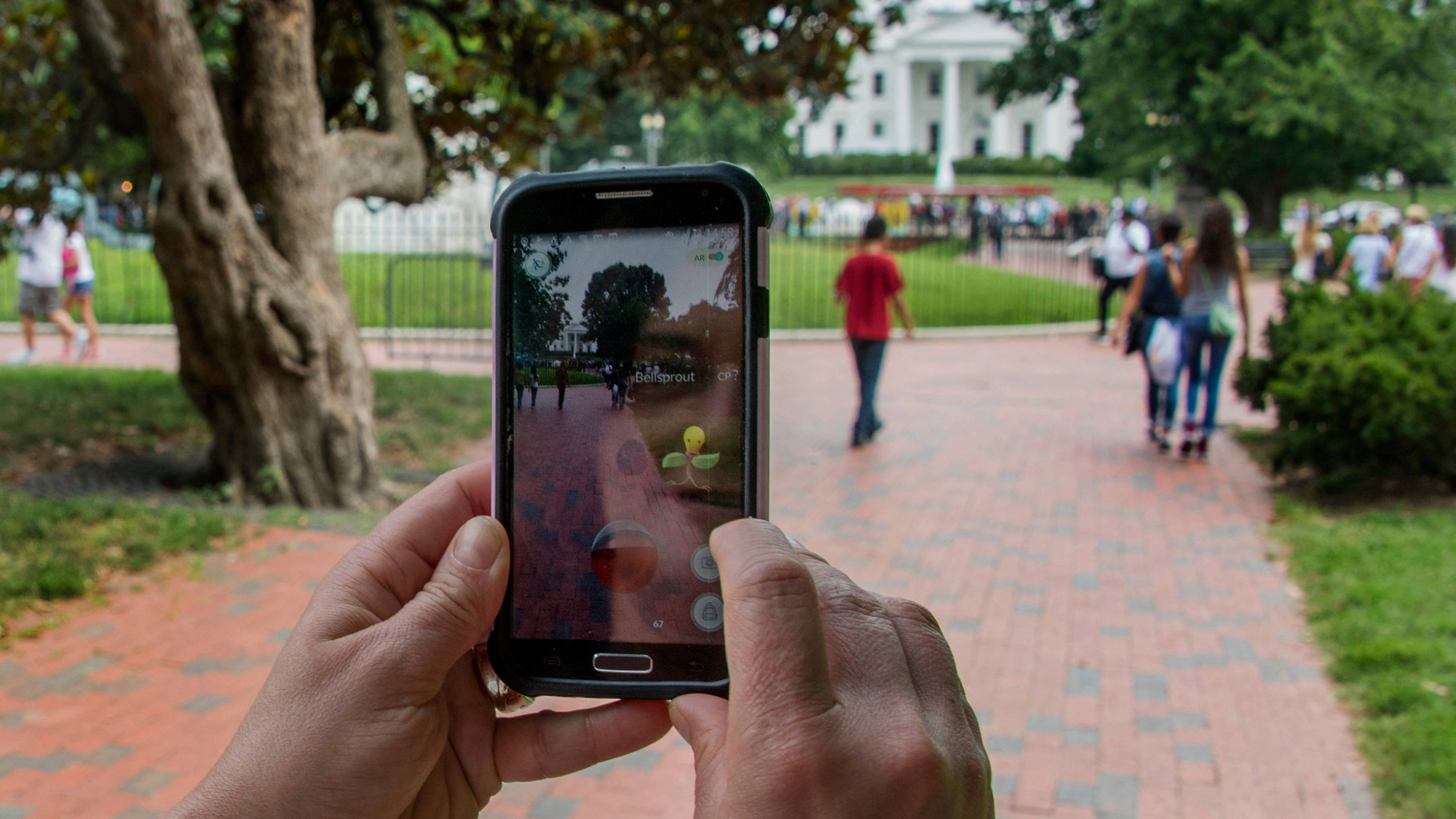 A woman holds up her cell phone as she plays the Pokémon Go game in Lafayette Park in front of the White House in Washington, DC on July 12, 2016.