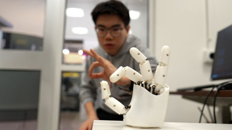a grad student works with a robotic hand that is directly mimicking its movement