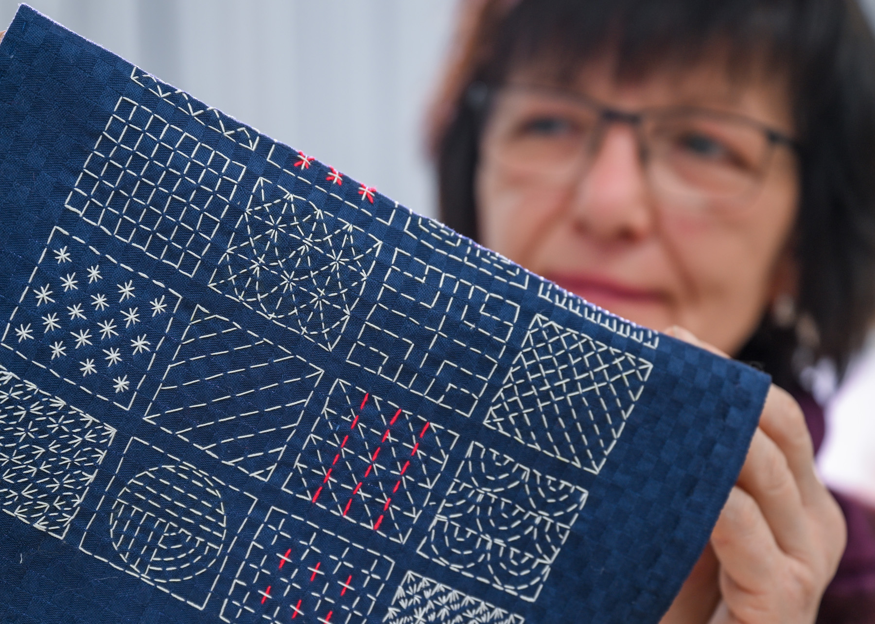 PRODUCTION - 13 December 2023, Saxony-Anhalt, Halle (Saale): In the textile restoration workshop at Burg Giebichenstein University of Art and Design Halle, workshop manager Ilona Fitzner shows a sample embroidery using the Japanese sashiko technique. The art academy is closing its textile restoration workshop at the end of the year. The search for larger orders proved difficult and the textile manufactory was put to the test. Creating a pure restoration course was out of the question for the university. It is well worth looking back. Valuable pieces, such as the Parade Bedroom for the Dresden Royal Palace, passed through the hands of the restoration team here. Photo: Hendrik Schmidt/dpa (Photo by Hendrik Schmidt/picture alliance via Getty Images)