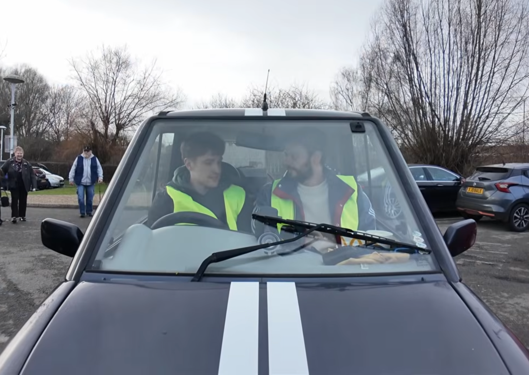 two men wearing neon vests in a small electric car