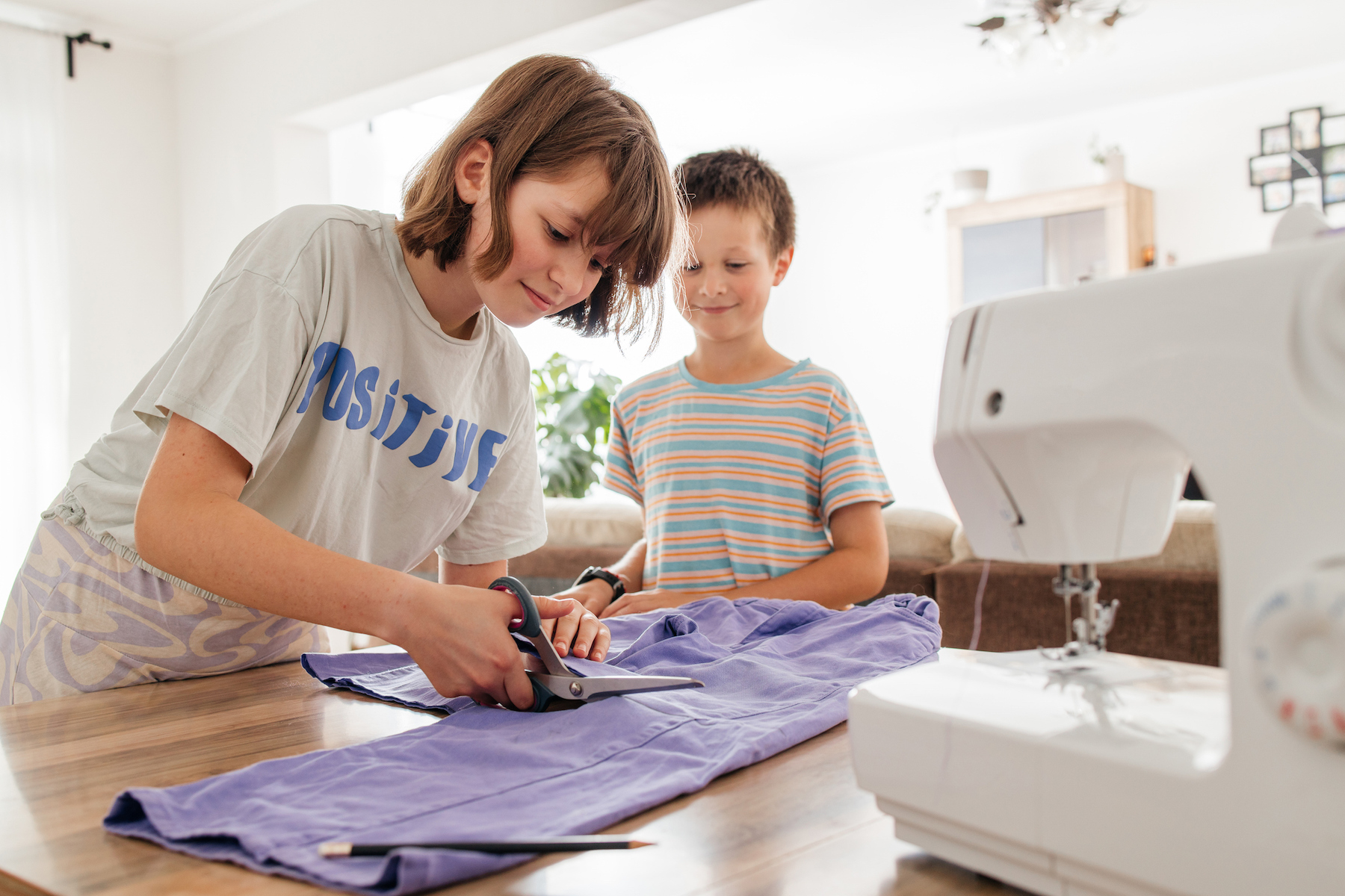 Teenage girl makes new shorts from old jeans, remake old things. Girl cuts fabric with scissors