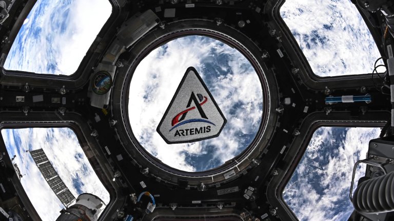 Artemis patch against capsule window in Orion with Earth beneath it