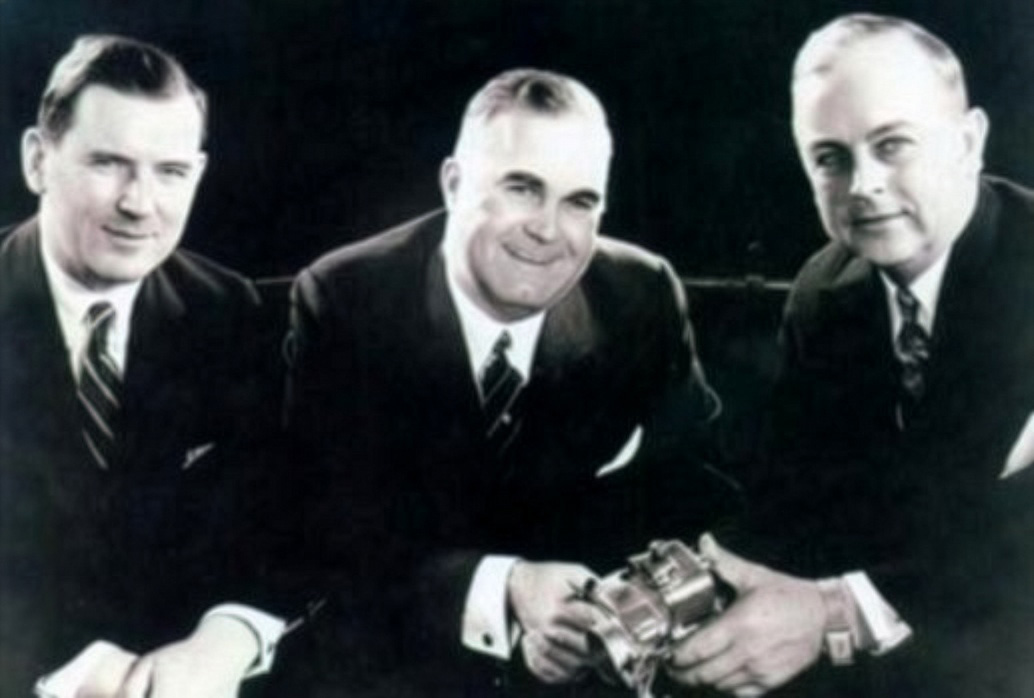 Black and white image of three middle aged white men in suits.