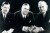 Black and white image of three middle aged white men in suits.