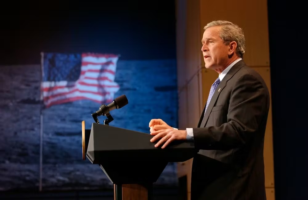 President George W. Bush in a suit stands at podium with a mic announcing his administration’s Vision for Space Exploration at NASA Headquarters in Washington, D.C., on Jan. 14, 2004.