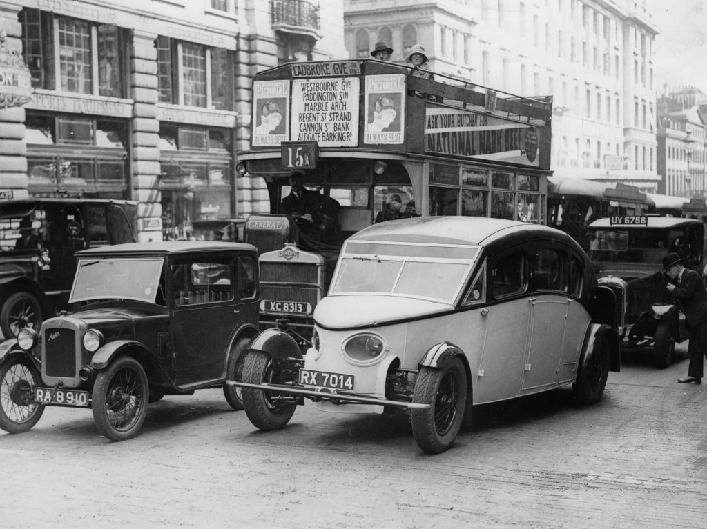 Black and white vintage photograph from 1930 showing a teardrop-shaped car driving through central London.
