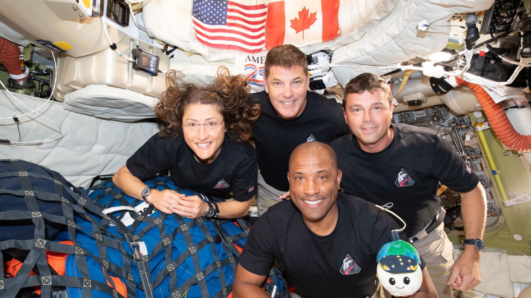 The Artemis II crew—(clockwise from left) Mission Specialist Christina Koch, Mission Specialist Jeremy Hansen, Commander Reid Wiseman, and Pilot Victor Glover—pause for a group photo with their zero gravity indicator “Rise,” inside the Orion spacecraft on their way home on April 7, 2026.