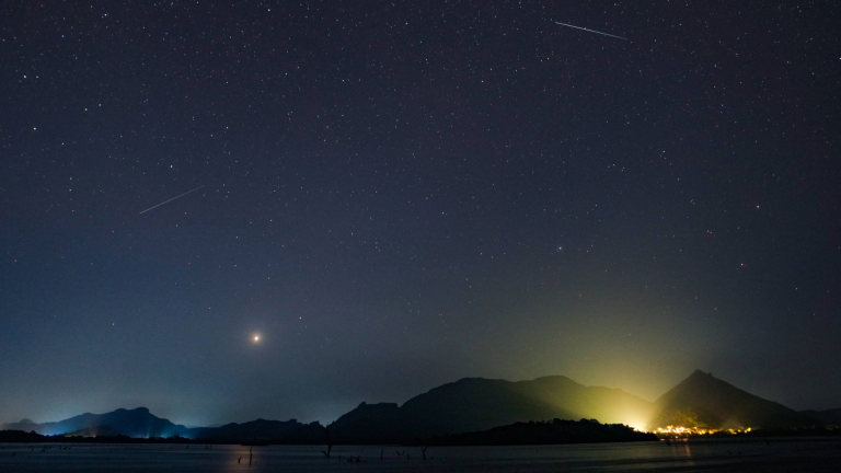 two meteors falling in a starry sky over mountains