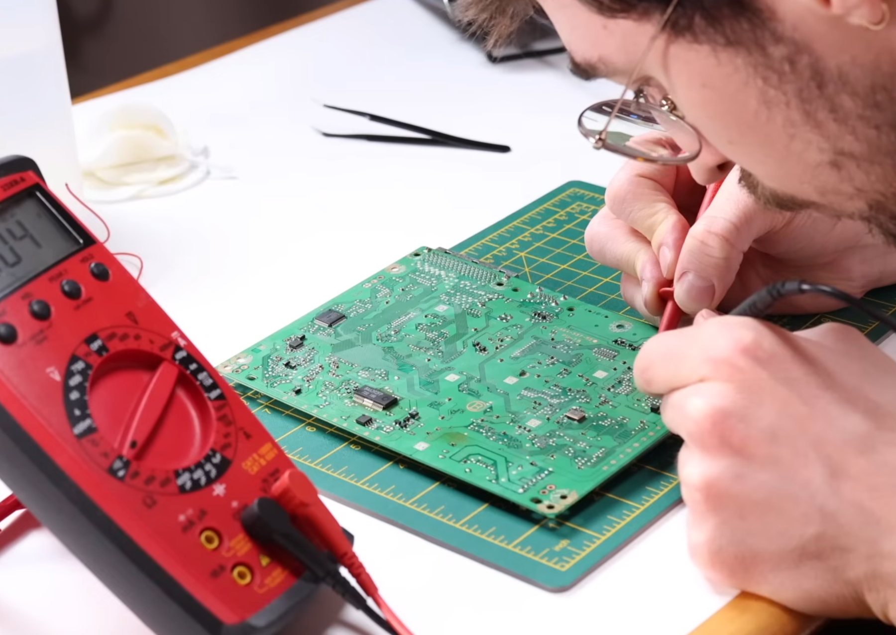 a man crouched over a green circuit board and working on it