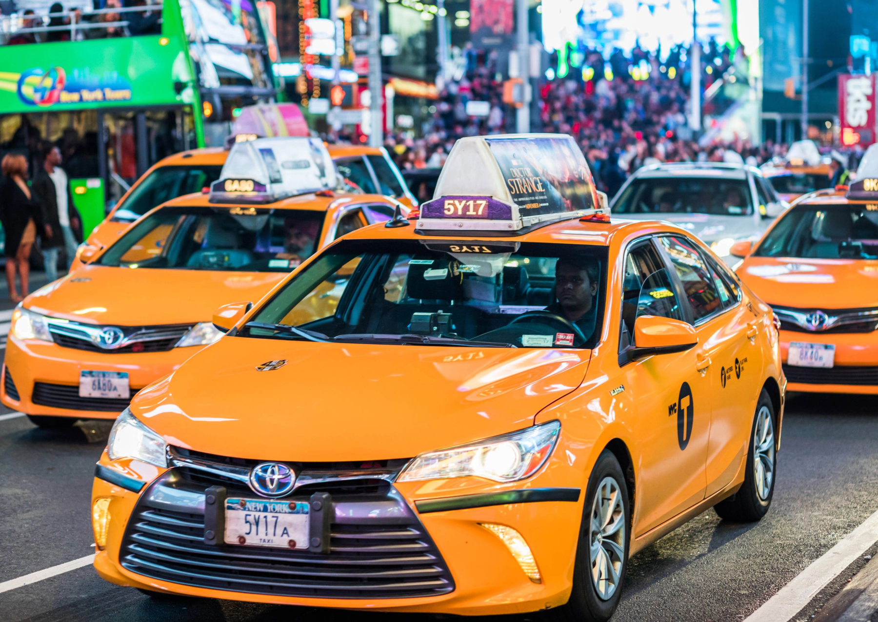 yellow taxies driving in times square in new york city at night