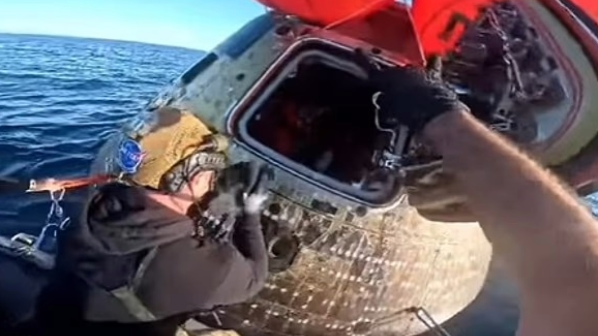a recovery crew opening up a space capsule int he ocean