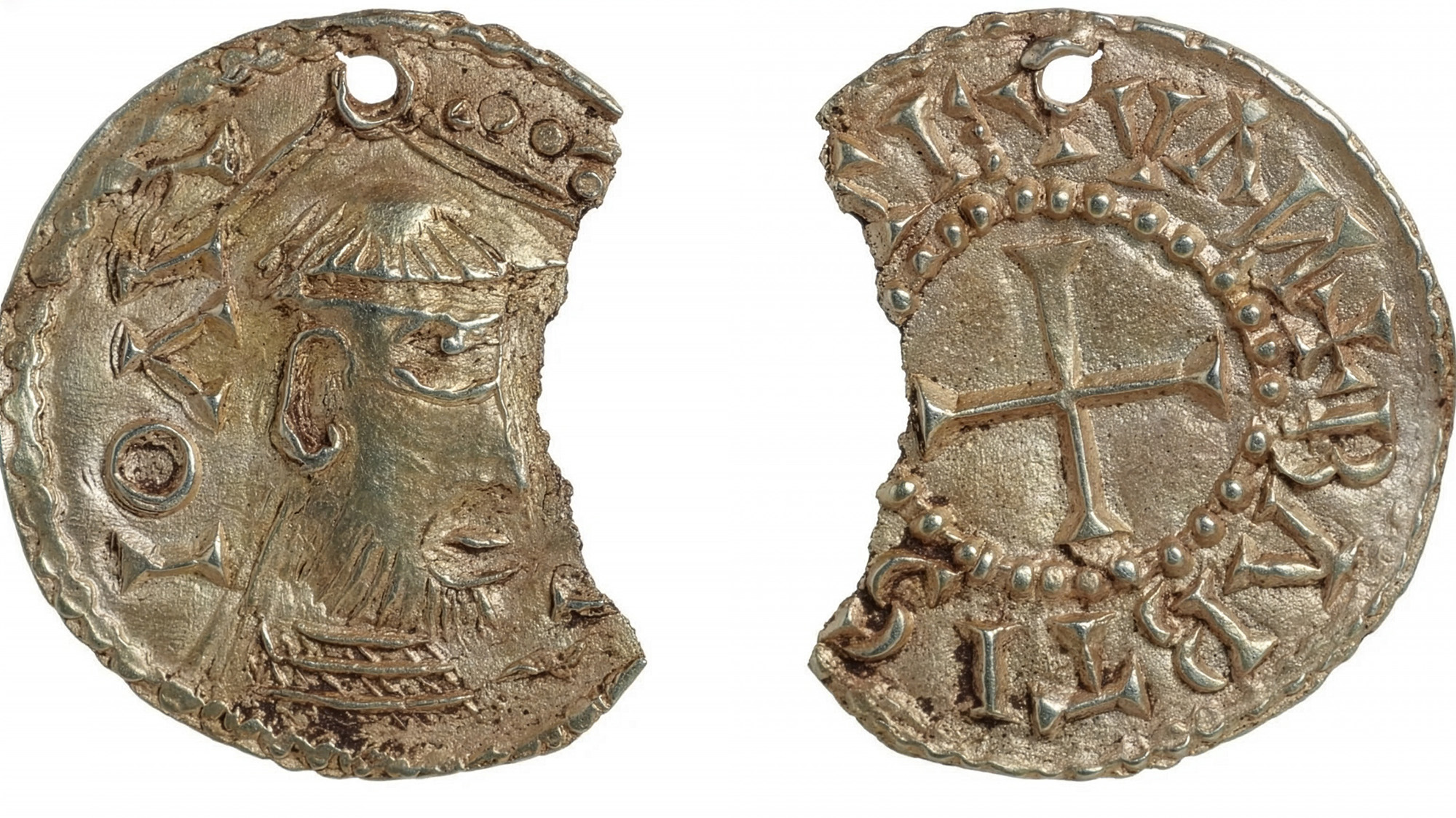 A high-resolution photograph shows both sides of a damaged, circular silver-gilt pendant depicting John the Baptist. The artifact is chipped on the right side and features a small suspension hole at the top. The obverse (left) shows a profile view of a bearded figure wearing a crown or headdress, while the reverse (right) features a central equal-armed cross enclosed in a beaded circle and surrounded by medieval-style lettering.