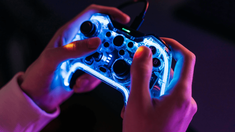 a person holds a video game controller illuminated by white light with dark buttons
