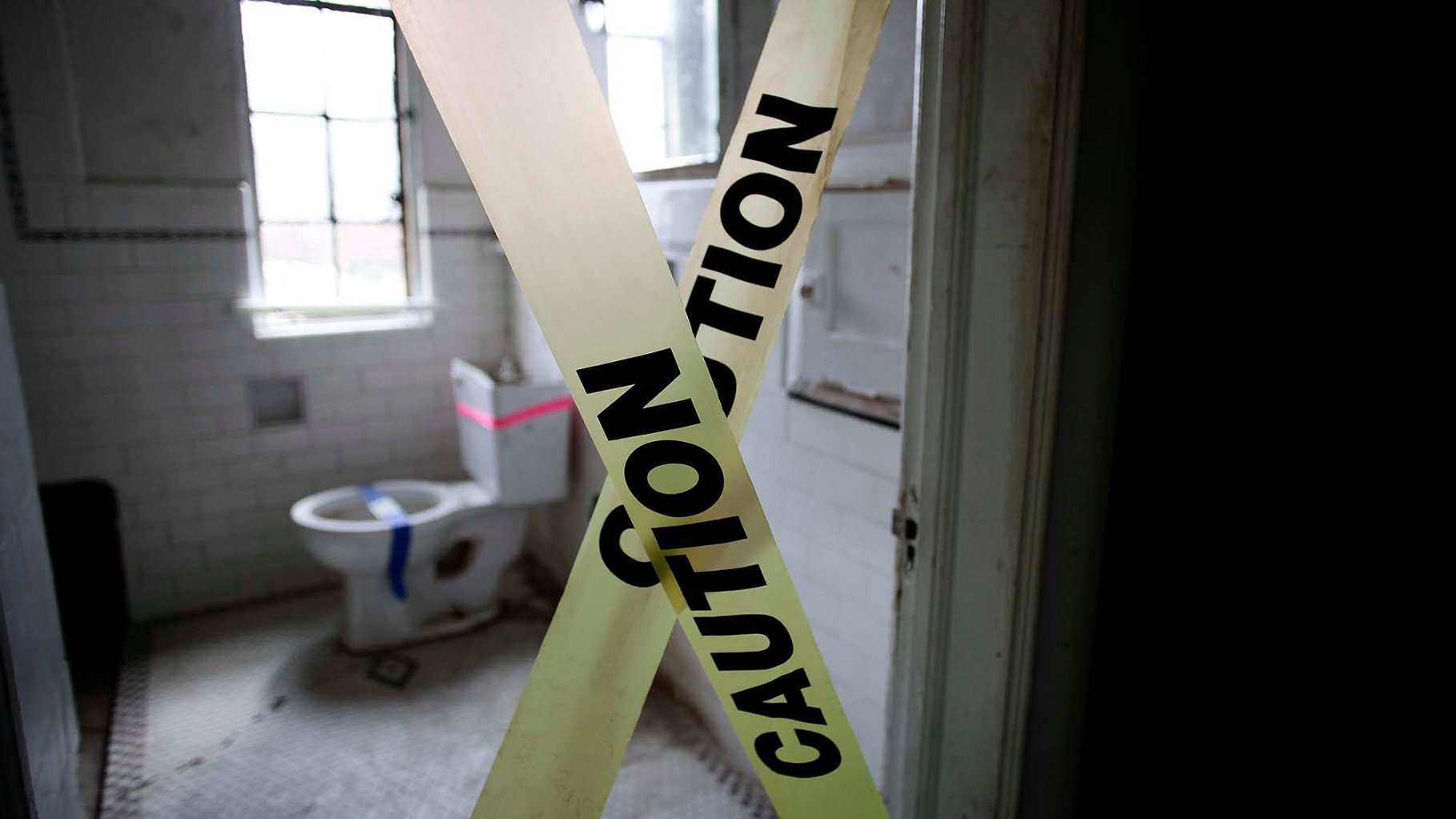 Caution tape blocks the entrance of a bathroom.