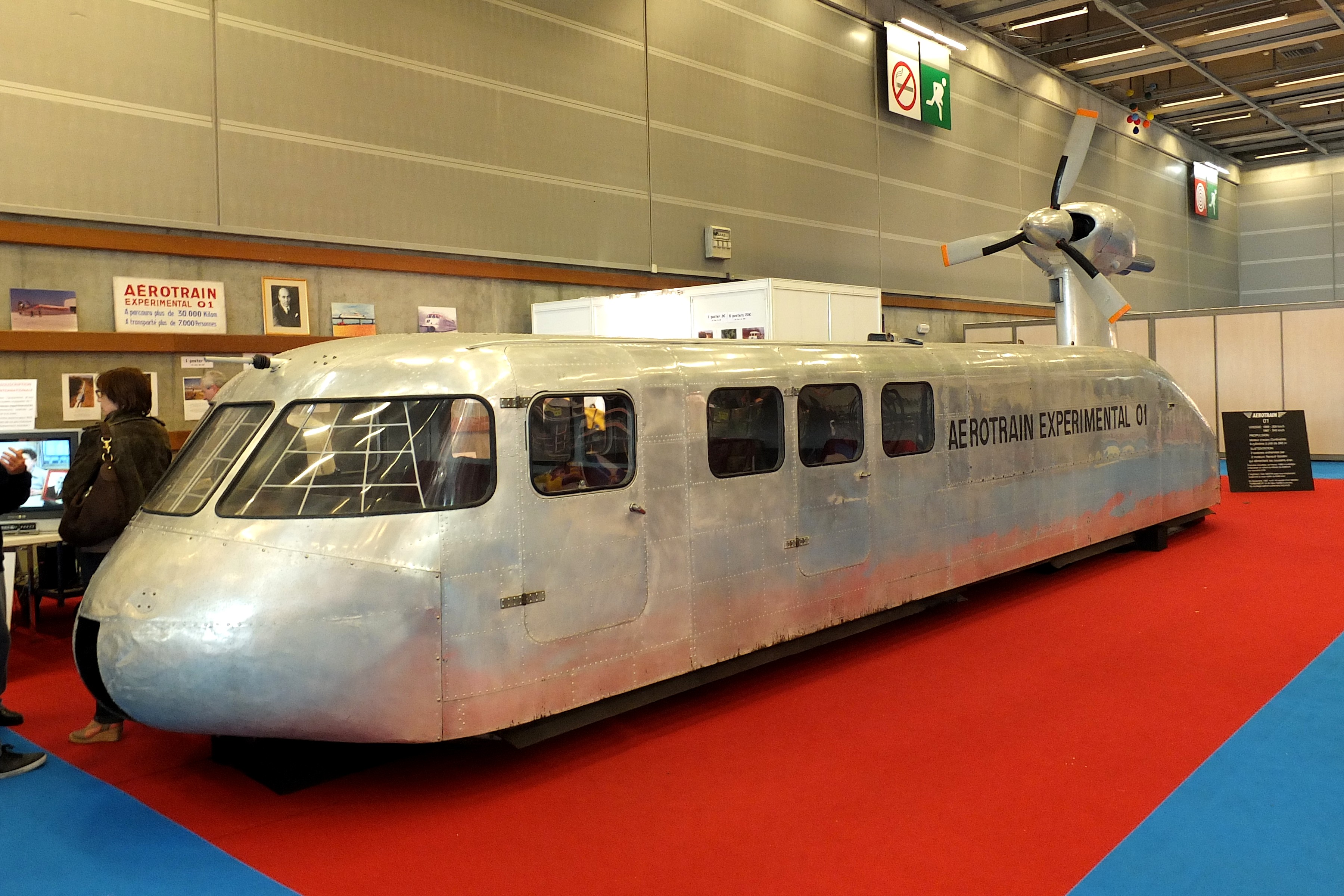 A metal hovertrain that kind of looks like a long AirStream with a turbine on its back in a museum display.