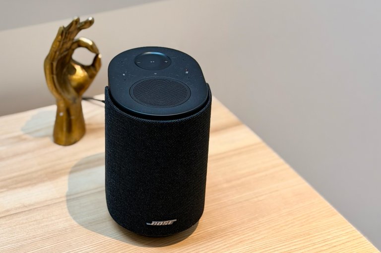 A Bose Lifestyle Ultra Speaker in Black sitting in front of a gold hand statue making the OK sign