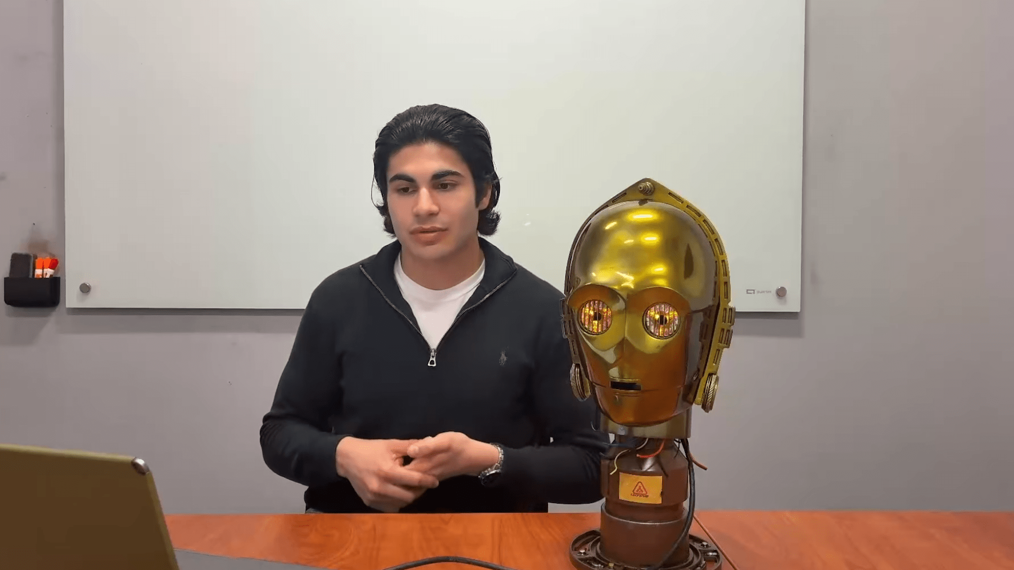 Man sitting next to C-3PO replica head
